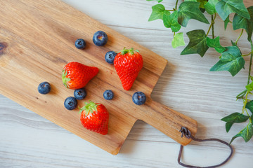 Strawberry and blueberry on cutting board.  まな板の上のイチゴとブルーベリー