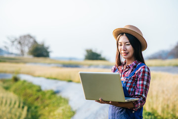 Smart Woman farmer looking barley field with laptop computer