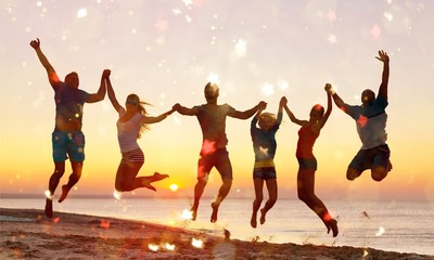 Naklejka na ściany i meble Friends jumping on beach at seaside at sunset
