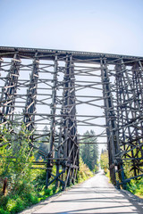 The road through the unique old tall Holcomb creek wooden train trestle wooden railway bridge across the valley