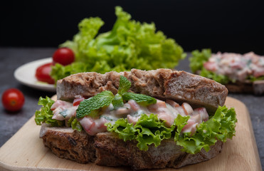 Healthy breakfast sandwiches with tomato, lettuce on gray board as background