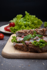 Healthy breakfast sandwiches with tomato, lettuce on gray board as background
