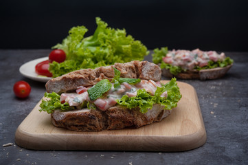 Healthy breakfast sandwiches with tomato, lettuce on gray board as background