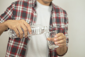 man hand holding a bottle of water Pouring water into a glass.