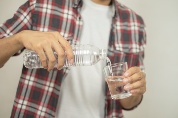 man hand holding a bottle of water Pouring water into a glass.