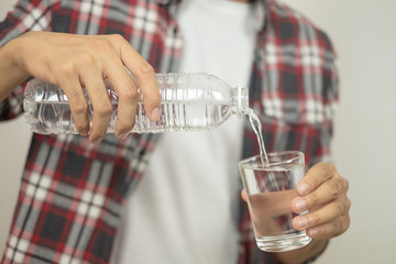 man hand holding a bottle of water Pouring water into a glass.