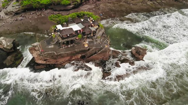 Ocean waves splashing at the rock formation of the Pura Tanah Lot Bali temple