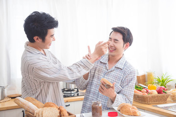 Young asian male homosexual couple wearing pajamas having beakfast in kitchen