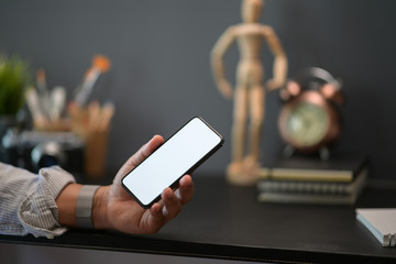Closes up man showing blank screen mobile phone at creative workspace
