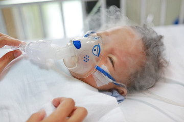 Naklejka premium Sick baby boy and has inhalation therapy by the mask of inhaler on patient bed at hospital. Respiratory Syncytial Virus (RSV).