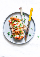 Baked chicken fillet stuffed with tomatoes and mozzarella on a light background, top view
