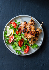 Turkey skewers and vegetables fresh salad on a dark background, top view