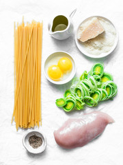 Chicken, leek, linguine pasta, parmesan cheese, eggs yolks, olive oil - ingredients for cooking carbonara pasta on a light background, top view