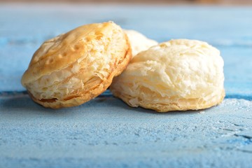 Mini cheese filled baked pies isolated on blue wooden background © remus20