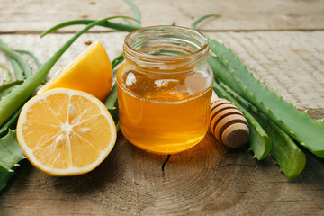 Healthy ingredients for strengthening immunity on wooden background - honey in jar, lemon and aloe...
