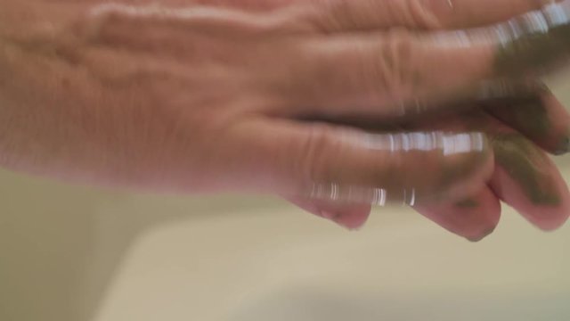 Macro lens Closeup: Man rubs mud of a dead sea mud mask between his hands.