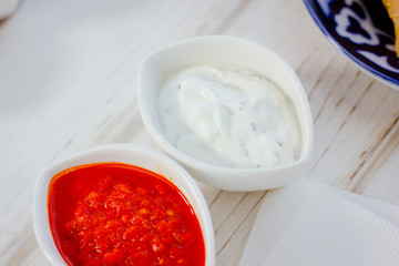 Different dips and sauces - red, white and black over white table.
