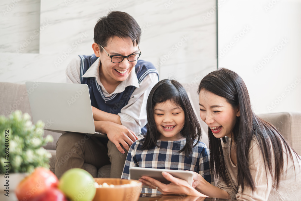 Wall mural Happy Asian family using tablet, laptop for playing game watching movies, relaxing at home for lifestyle concept