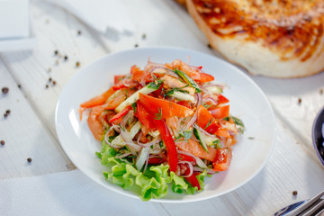 Vegetable salad on the white plate. Achik Chukchuk salad with tomatoes and onion.