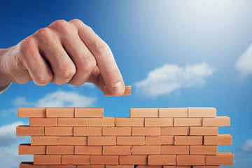 Businessman puts a brick to build a wall. Concept of new business, partnership, integration and...