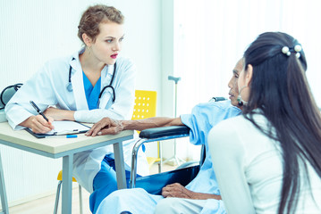 Fototapeta premium Young professional female doctor helping hands ,explaining diagnosis to senior man patient in medical office at hospital/ clinic .Elderly care medicine, age, health care, cardiology and people concept