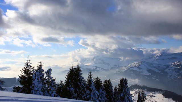 Time-lapse showing moving clouds over mountain peaks in the French Alps in winter, with evening light. From the resort of Praz sur Arly