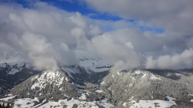 Time-lapse of winter mountain scenery , with rolling clouds and alpine peaks in the French Alps near the resort of Praz Sur Arly