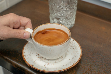 Hand taking a cup of long black coffee