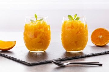 Fresh orange citrus sorbet garnished with mint - traditional cold dessert. Homemade fruit sorbet in a glass.