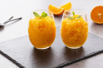 Fresh orange citrus sorbet garnished with mint - traditional cold dessert. Homemade fruit sorbet in a glass.