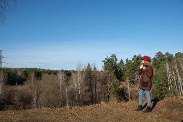 Female model in a red hat and autumn coat in the woods for a walk.