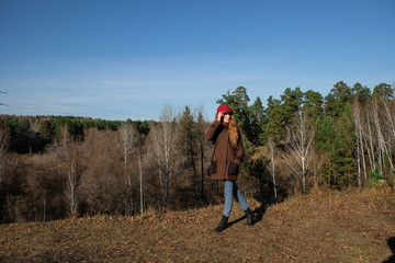 Fototapeta na wymiar Female model in a red hat and autumn coat in the woods for a walk.