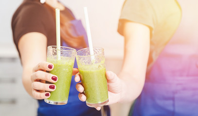 Hands of young girls hold in glasses detox smoothies, green color, close-up