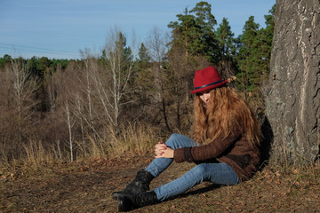 Female model in a red hat and autumn coat in the woods for a walk.