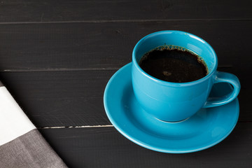 Cafe en taza azul con plato que le hace juego en fondo de madera negra