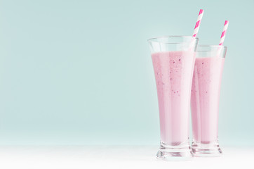 Blueberry smoothies with straws in high glass on white wood table and pastel blue wall, copy space.