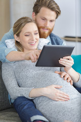 Fototapeta premium pregnant woman looking at a tablet with her partner