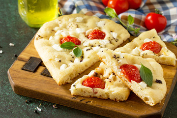 Traditional Italian Focaccia with rosemary, tomatoes and feta - homemade flat bread focaccia.