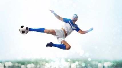 Soccer striker hits the ball with an acrobatic kick in the air on white background