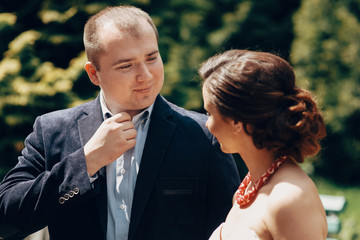 Portrait of happy newlywed couple, happy handsome groom and beautiful bride in elegant dress smiling in sunny park, cute moment before marriage