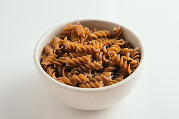 Whole grain fusilli pasta on white background