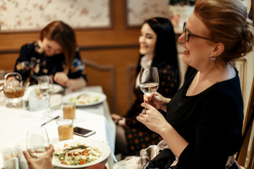 group of luxury elegant women celebrating with champagne and  laughing in rich restaurant