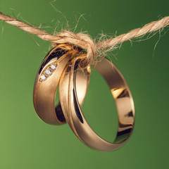 Two wedding rings tied with a rope on a green background