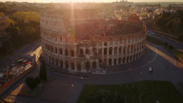 aerial view of colosseum at sunrise flying backwards rise up rome italy