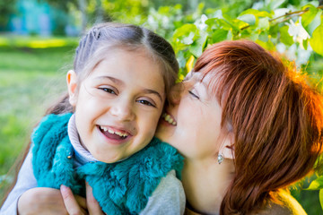 Mother and daughter having fun near blossom apple trees