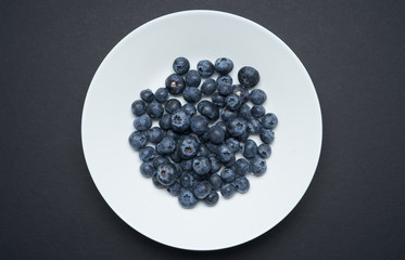 Closeup view of fresh blueberry on White plate ,black background