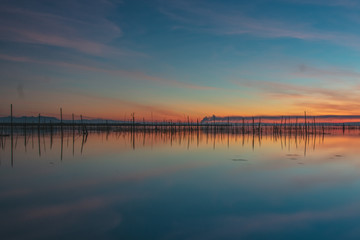 Sunset landscape views of a natural lagoon with a sunset and mountains in the background in Albufera of Valencia