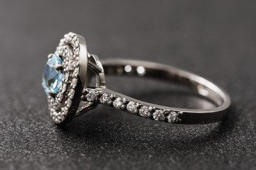 Side view of a gold ring with cubic zirconias and large topaz on an abstract background, close-up