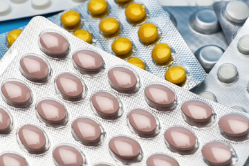 Pile of colorful medicine pills and capsules . A lot of packages of multicolored pills lying on blue background