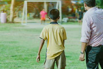 Fototapeta premium Asian boys practice kicking the ball to score goals in the public football field.